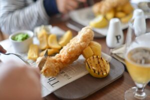 Fish and chips britannique servi avec un flacon de vinaigre de malt